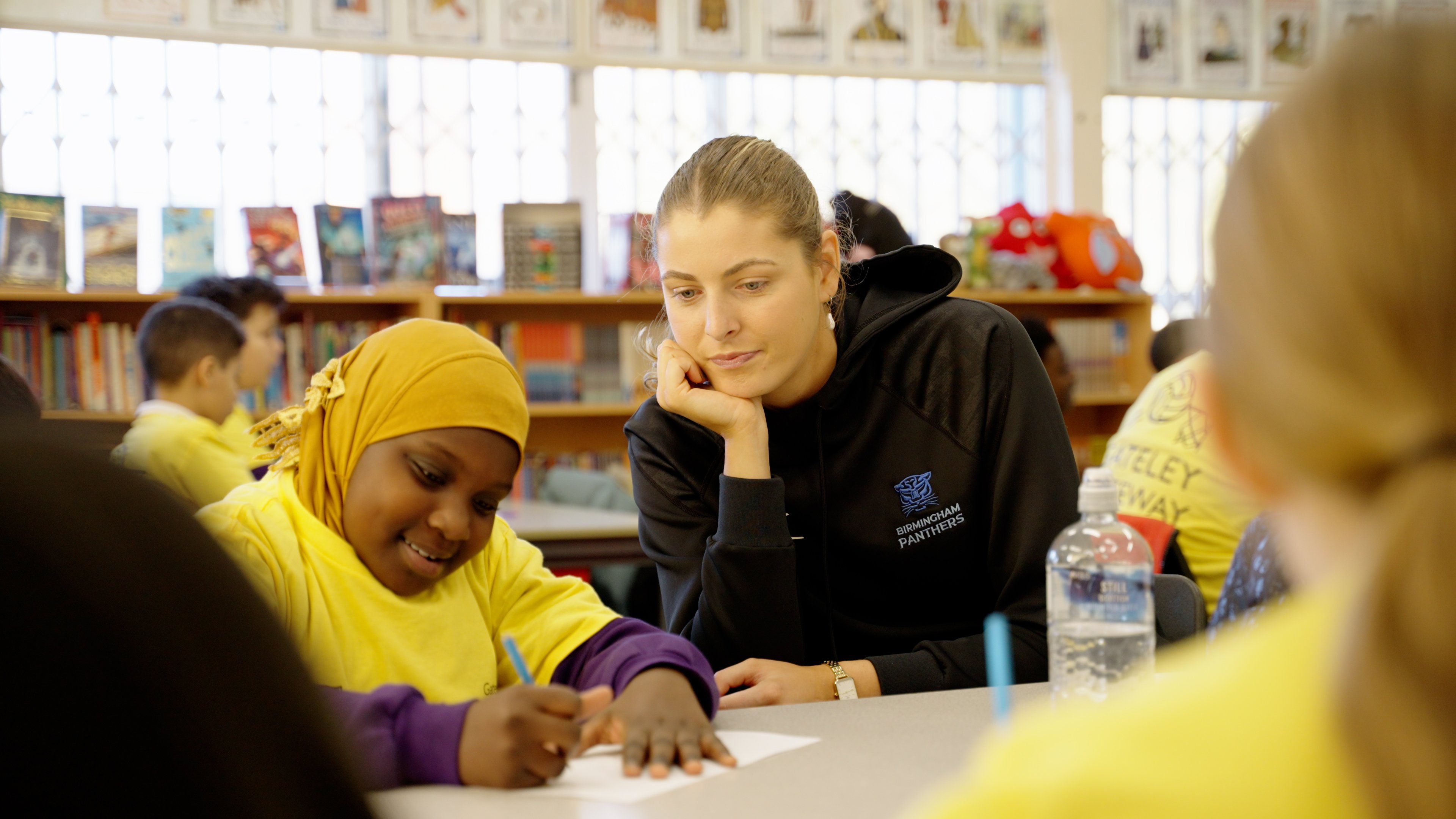 One of the players helping one of the children with her school work