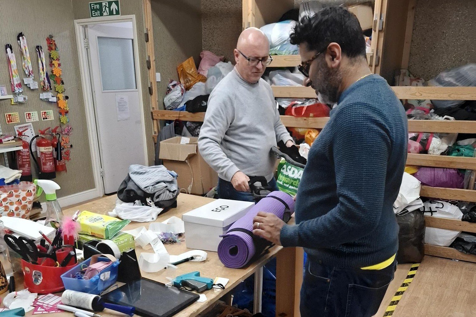 Photo of our two team members in the sorting room, organising donations
