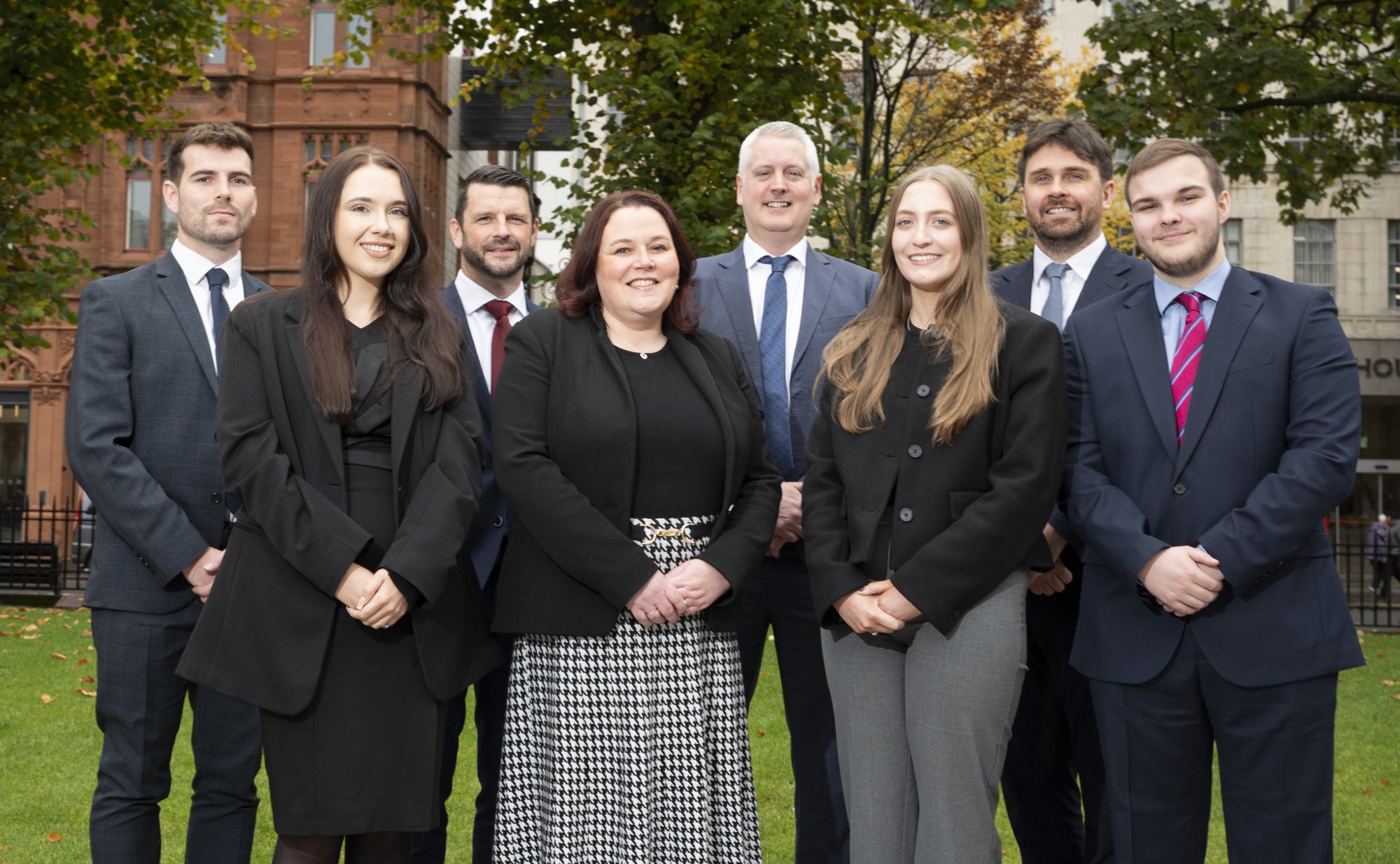 Our new Belfast team stand in two rows outside our office, smiling at the camera