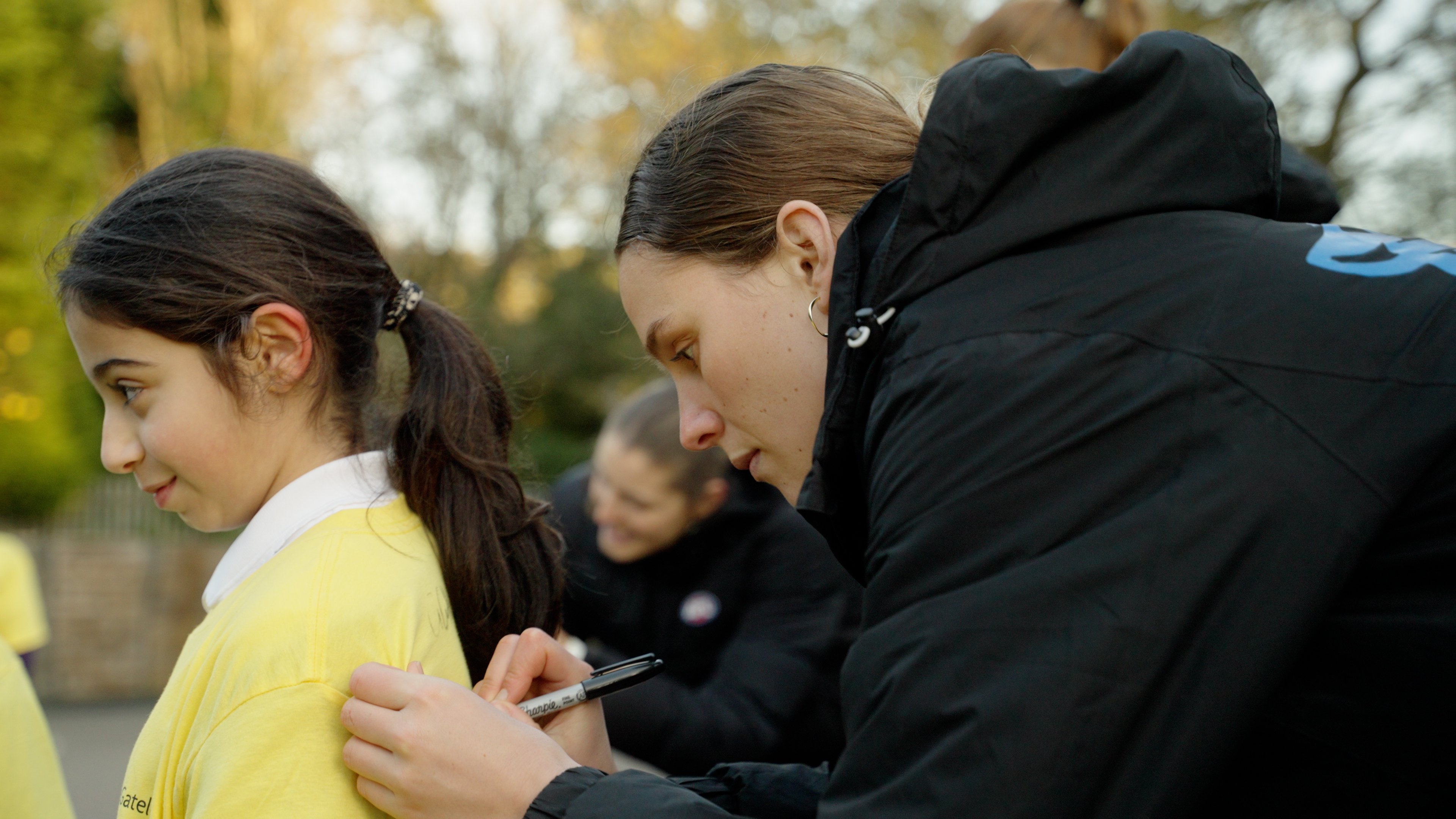 One of the players signing the shirt of one of the children