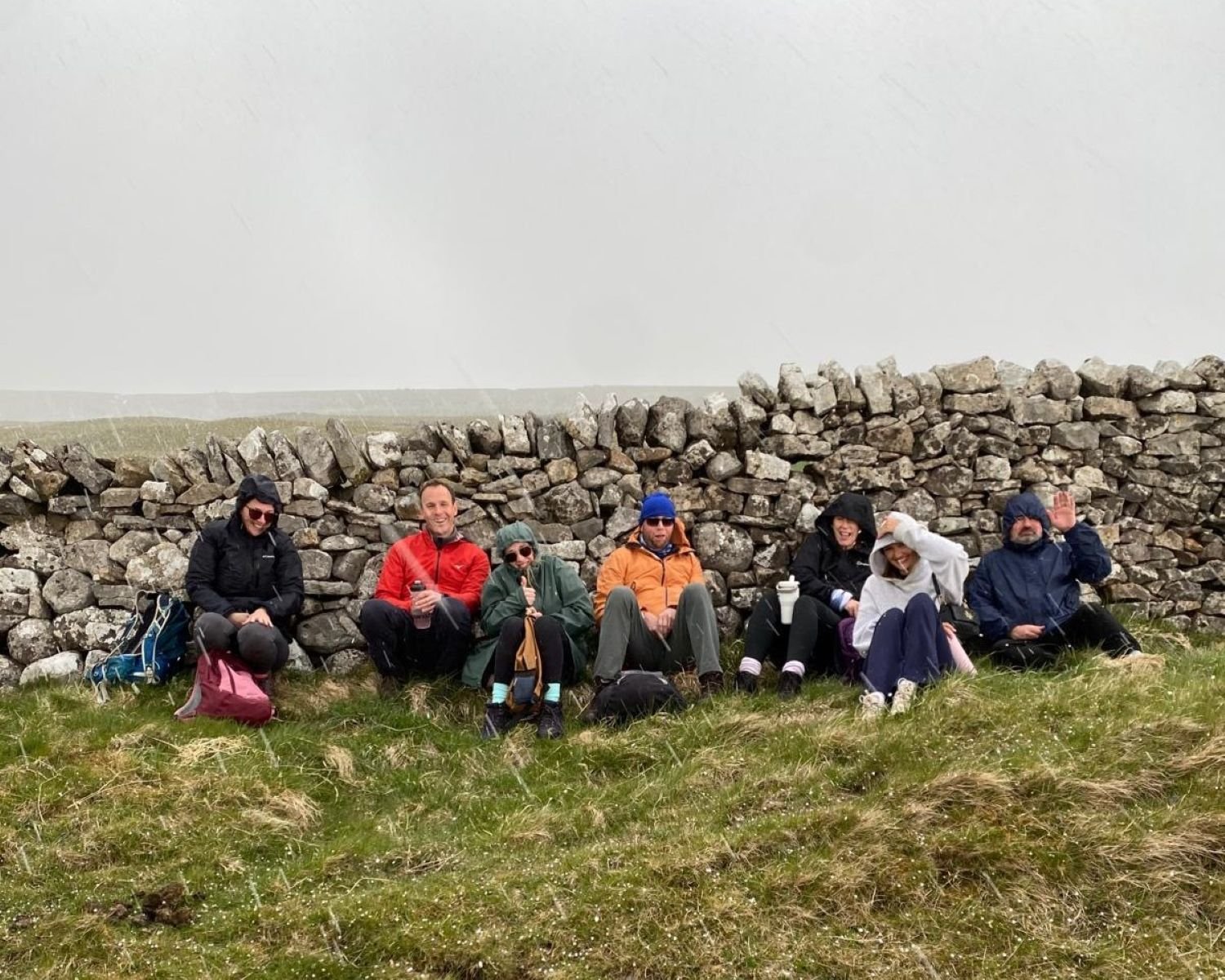 Some of the team sheilding from the rain behind a rock wall